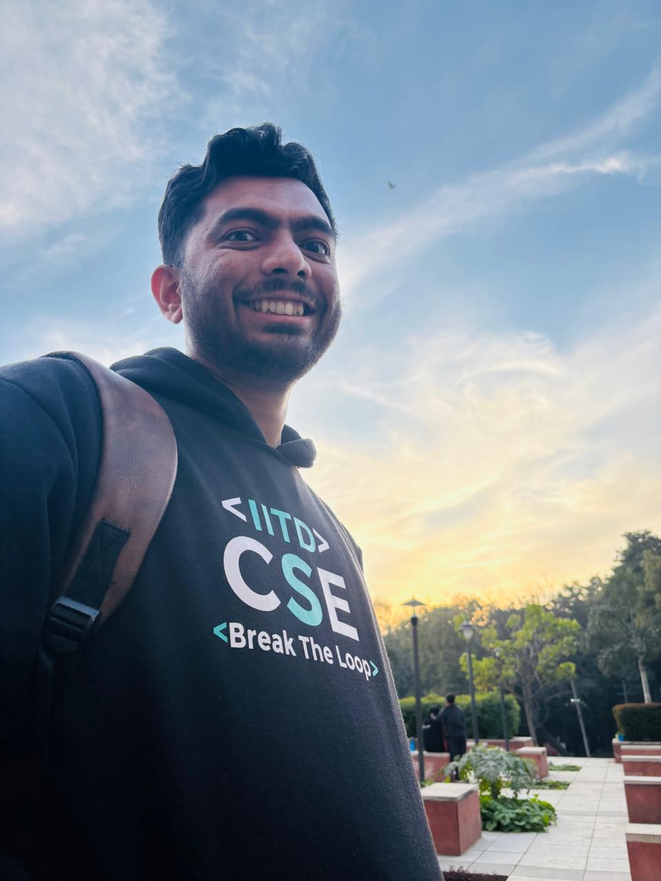 Saharsh smiling in an IITD CSE hoodie against the evening sky